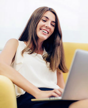 Frau sitzt entspannt auf der Couch und schreibt eine E-Mail